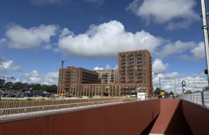 Nieuwe woongebouwen naast het spoor en een fietsonderdoorgang.